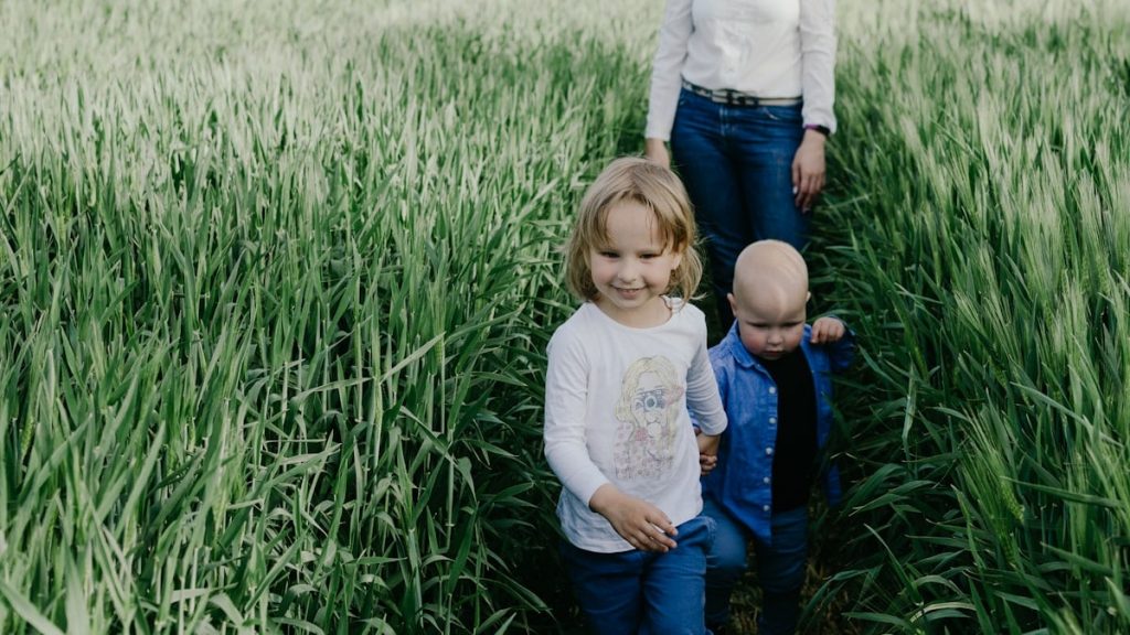 girl in white long sleeve shirt and blue denim jeans sitting on green grass field during